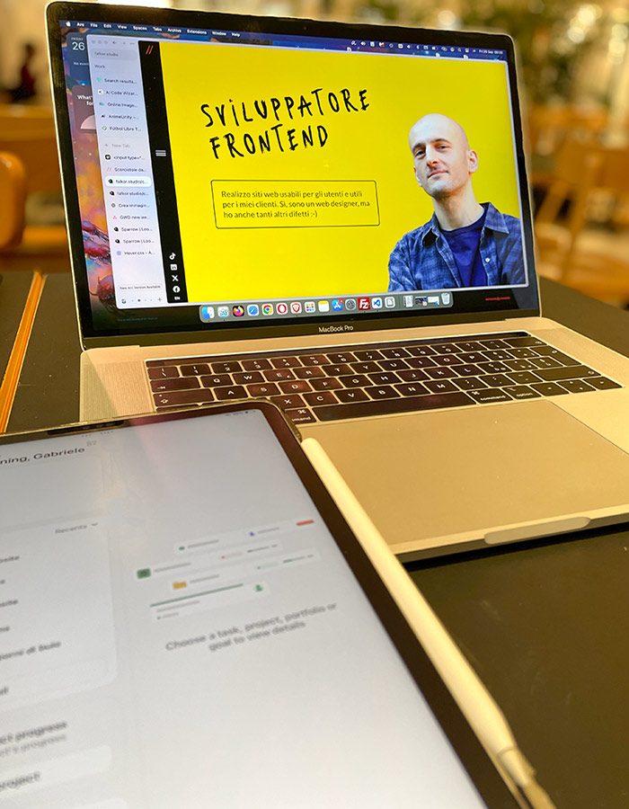 Un macbook aperto sul sito web di Gabriele Web Designer e un iPad su un tavolo in un cafè